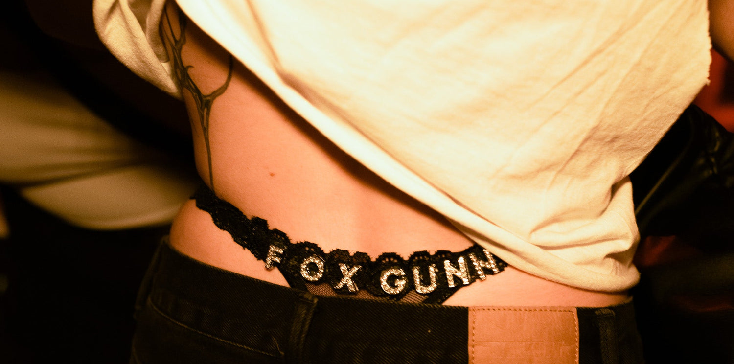 Fox wearing a black thong with 'FOX GUNN' branding.
